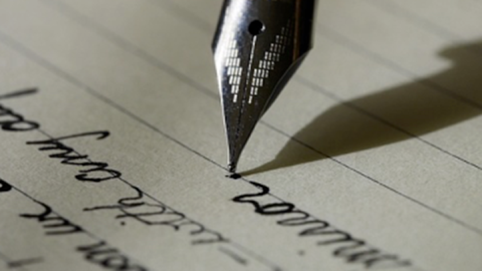 Foto di una penna stilografica che scrive su un foglio a righe