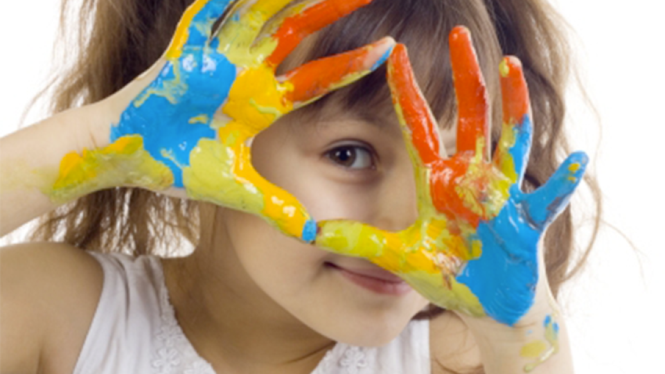 Foto di una bambina con mani aperte e colorate con la tempera